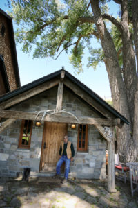Photo of John Foote next to a stone house addition